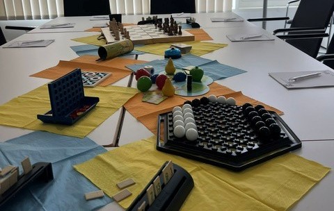 SkillSaga tabletop game setup with colorful paper maps, game boards, tokens and player pieces on a conference table